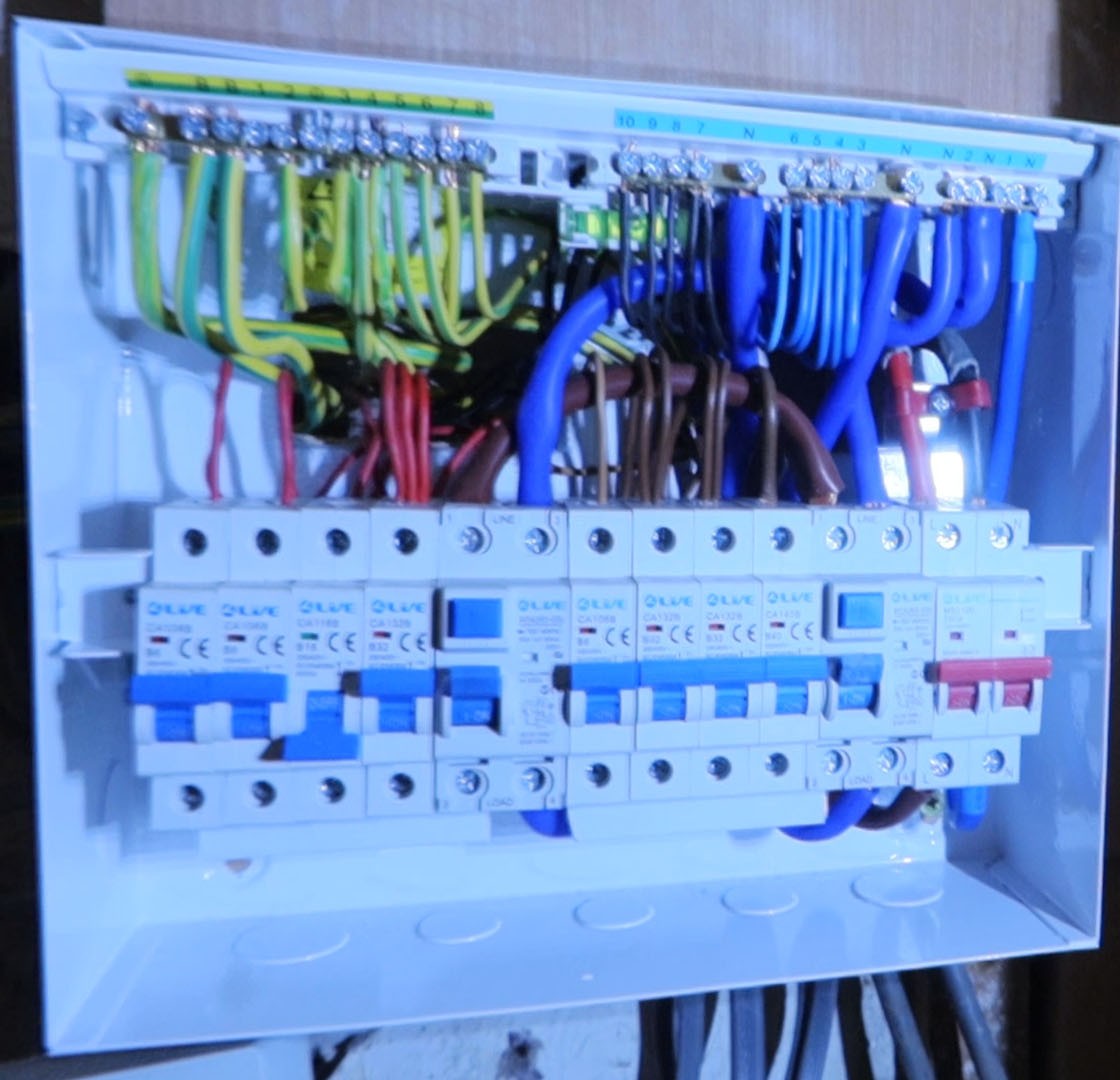 A newly wired consumer unit with its cover off, showing neat blue, brown and green cabling above a row of breakers