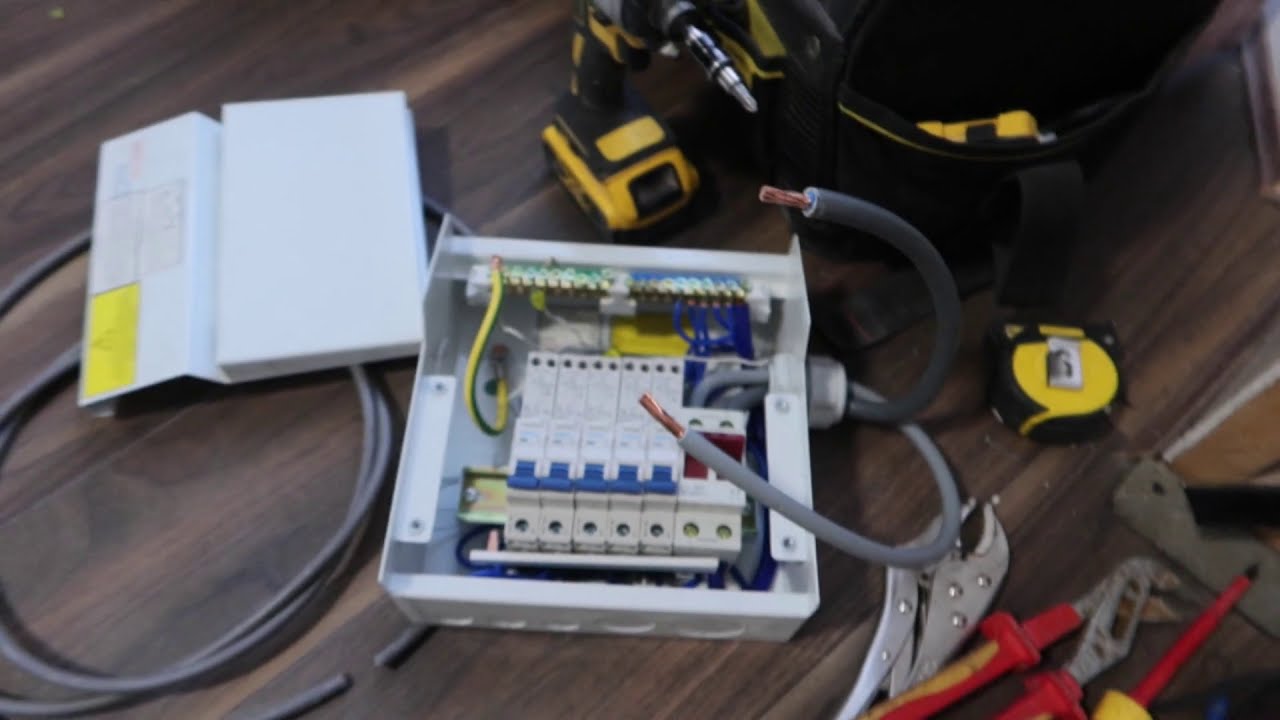 A small consumer unit with its cover off, lying among hand tools and a drill